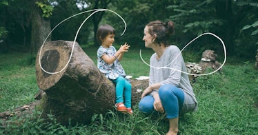 a mother and child sit outside on a log to talk