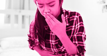 A young girl holding her tummy with her hand over her mouth