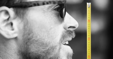 a yellow tape measure next to a man's face in profile with a greyscale edit