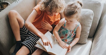 two children read a book together