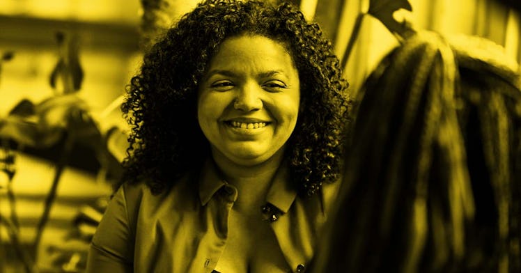 An black woman with dark curly hair smiles at the camera.