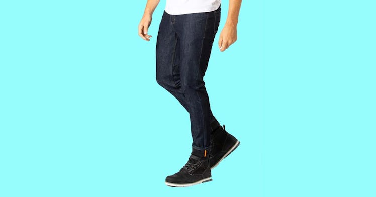 a person shown from the waist down wearing a dark-blue pair of men's stretch jeans and black shoes, ...