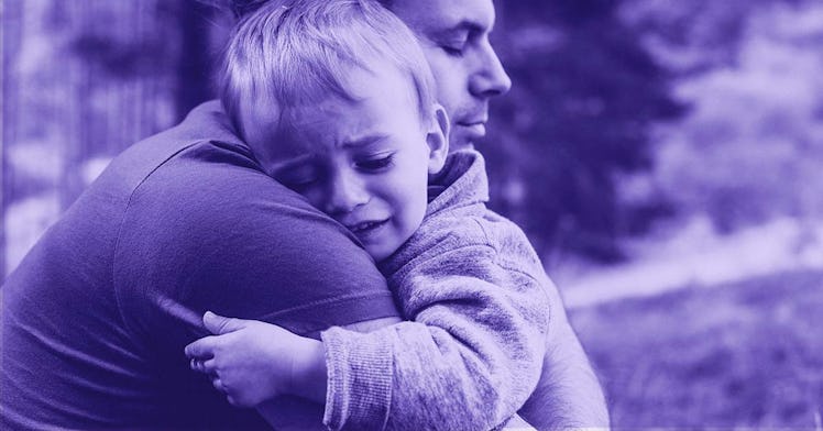 A small son crying on his dad's shoulder while hugging