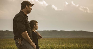 A father in a ballcap looks out at the horizon with his young son