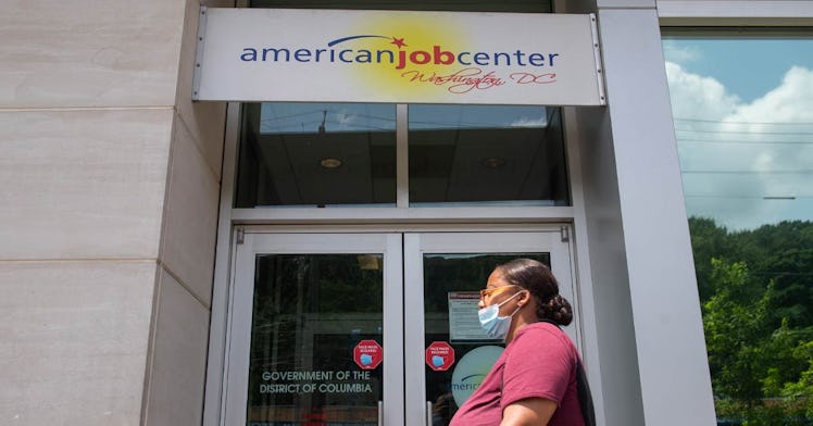 A woman walks past a job center in a mask