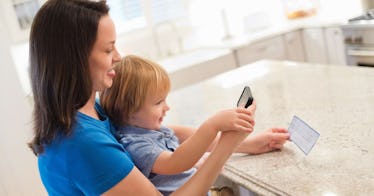 A person sits with a baby on their lap looking at their mail