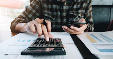 一个男人坐在他的办公桌和一个计算器