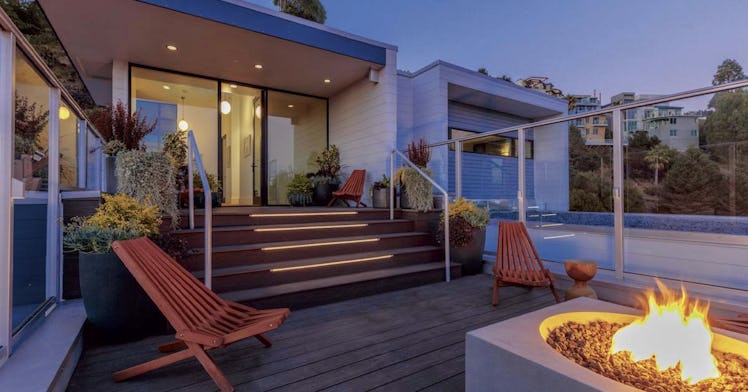 A beautiful deck, off of a modern home, with lounge chairs, a fire pit, and composite decking