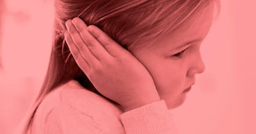 A little girl looks worried while putting her hand on her ear