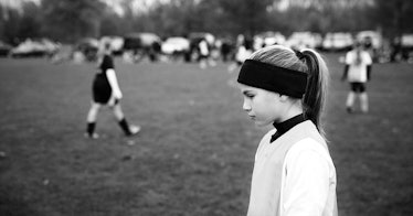 a girl in a black headband on a soccer field in black and white