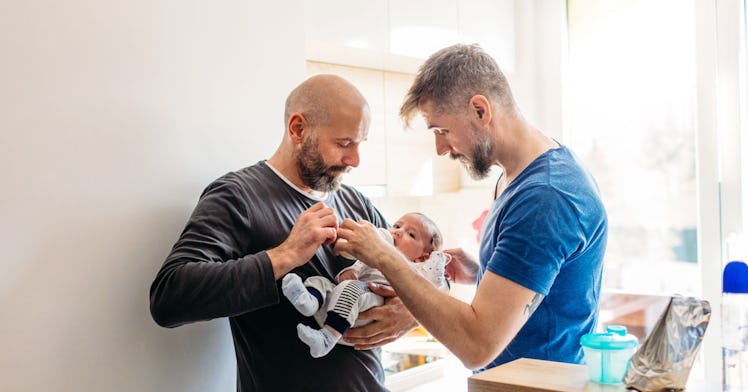 Two gay parents hold a baby