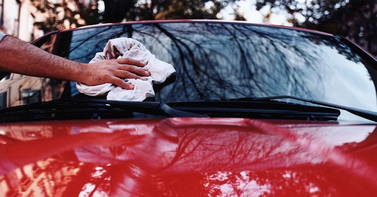 photo of a hand polishing the windshield of a shiny red car demonstrating how to wash your car