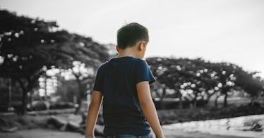 A boy stands outside near a body of water