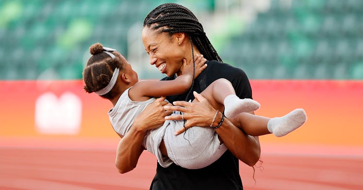 Alyson Felix holds her child on a track