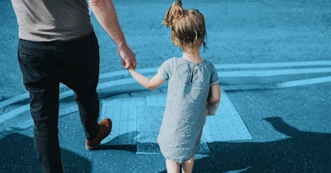 A young girl being led by the hand across the street in demonstration of authoritative leadership