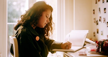 A teen at a desk writing in notebooks to plan an activity