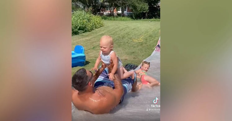 A dad holds his baby on a slip n slide