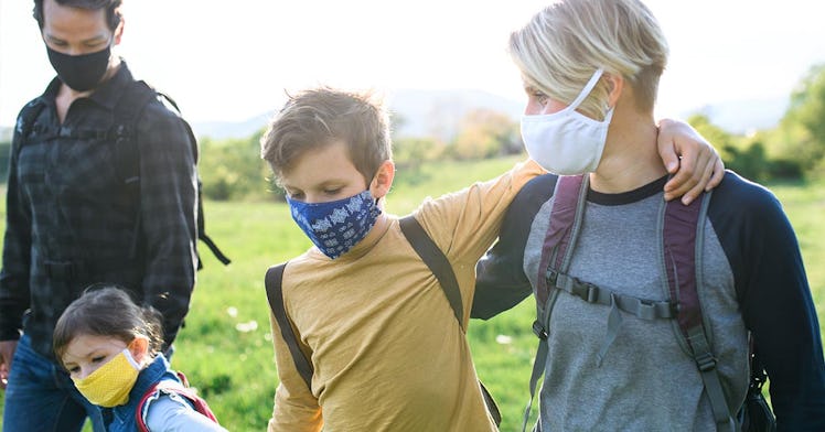 A family of 4 walks outside wearing a mask