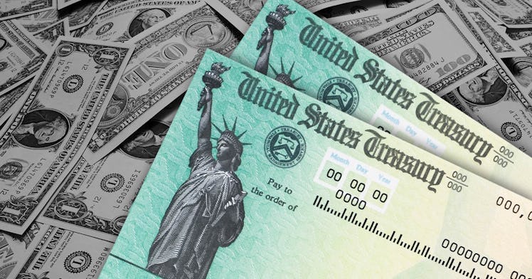 two stimulus checks sit on a pile of cash