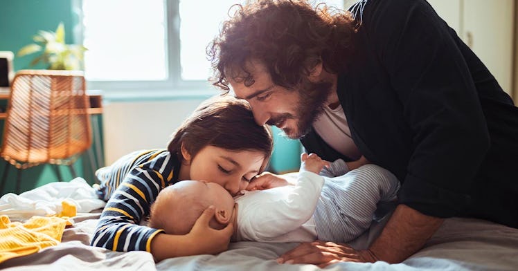a parent embraces his child and baby