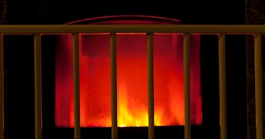 A fireplace glowing in the dark behind a baby proof gate.