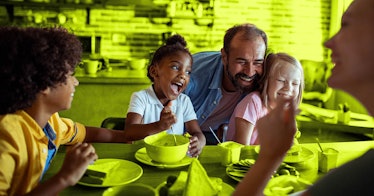 A blended mixed-race family laughs while at the dinner table