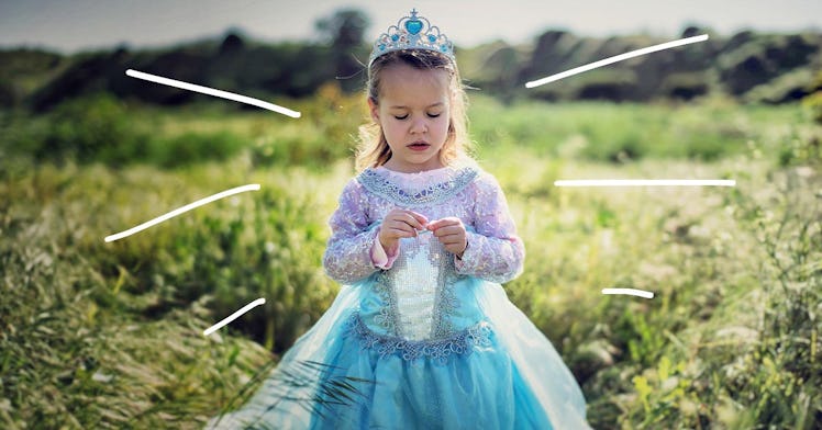 A little girl stands in a field wearing a princess dress