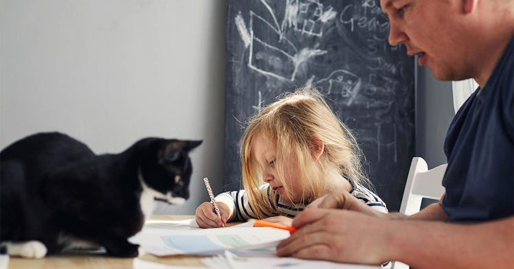 A girl, her dad, and a black cat sit at a table