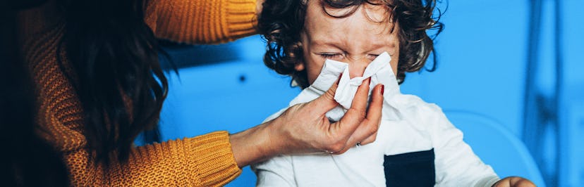 A mother helping her child blow their nose during the flu season.