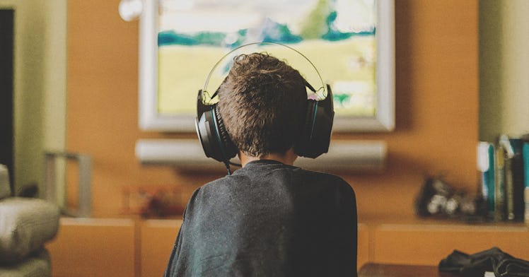 A kid faces away from the camera, playing video games with a headphone on