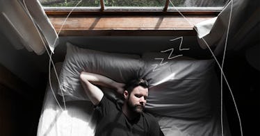 A man sleeps on his bed as the daylight shines down on him