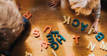 Two children play with toy letters on the floor