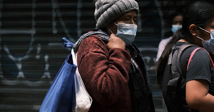 A person in a mask, carrying bags, walks