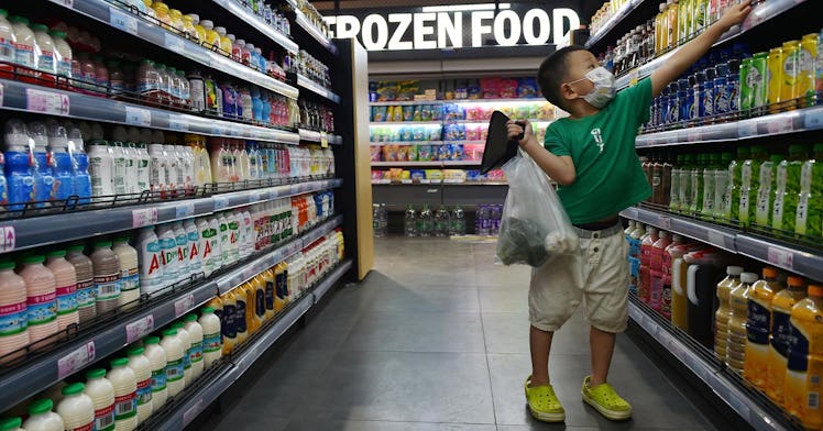 A kid in a mask reaches for food at a grocery store