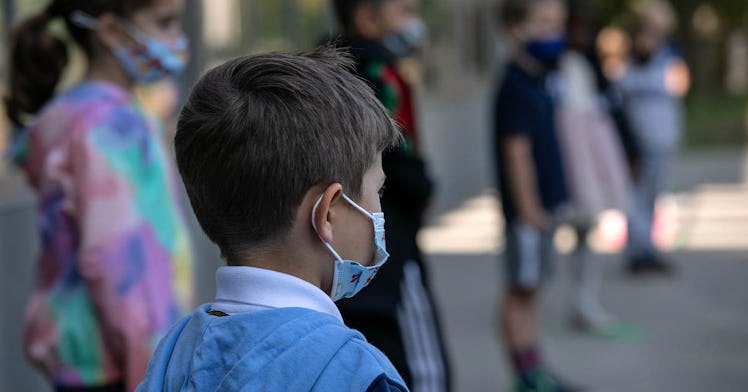 A little boy facing away from the camera wears a mask