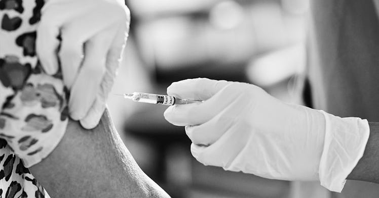 A person shoots a vaccine into an arm of a person