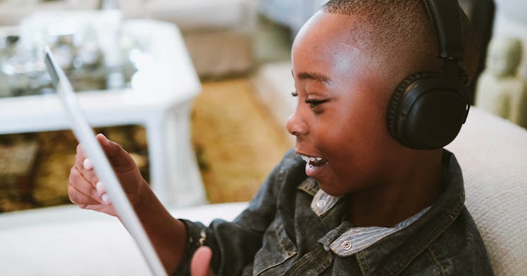 A kid sits on his tablet watching YouTube with headphones on