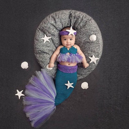 A baby lying while wearing a Mermaid costume