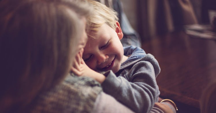 A small child smiles in their mom's arms