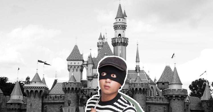 A burglar in a burglar outfit stands in front of Disney castle