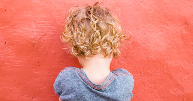 a little kid with blonde, curly hair faces away from the screen