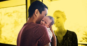 A new dad holds his child while a mother looks on.