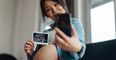 a pregnant woman shows a picture of her ultrasound on a video call