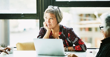 A middle-aged person sits at a table with a laptop