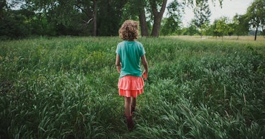 a child walks through a green field