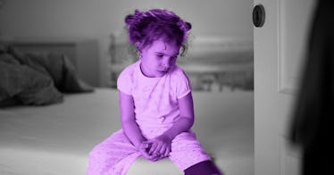 Sad little girl sitting on her bed alone in her room
