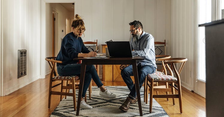 Two parents sitting at their dining table, with notebooks and laptops out