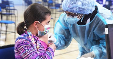 A young kid looks at a vaccine worker