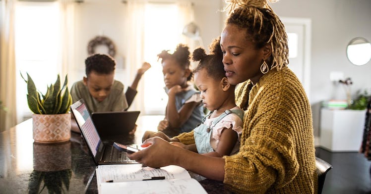 A mother working from home while her three kids are sitting next to her