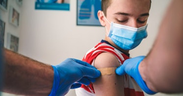 戴着口罩的孩子在接种疫苗后，手臂上贴着创可贴
